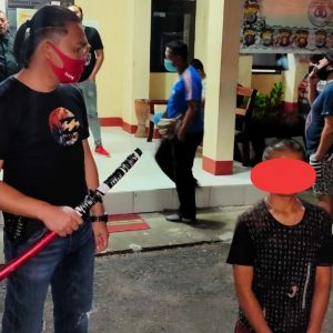 Pelaku (kanan) saat diamankan di kantor Mapolsek Tomohon Tengah. Katim URC Totosik Bripka Yanny Watung (kiri) memegang barang bukti berupa sebilah parang jenis samurai yang digunakan pelaku.